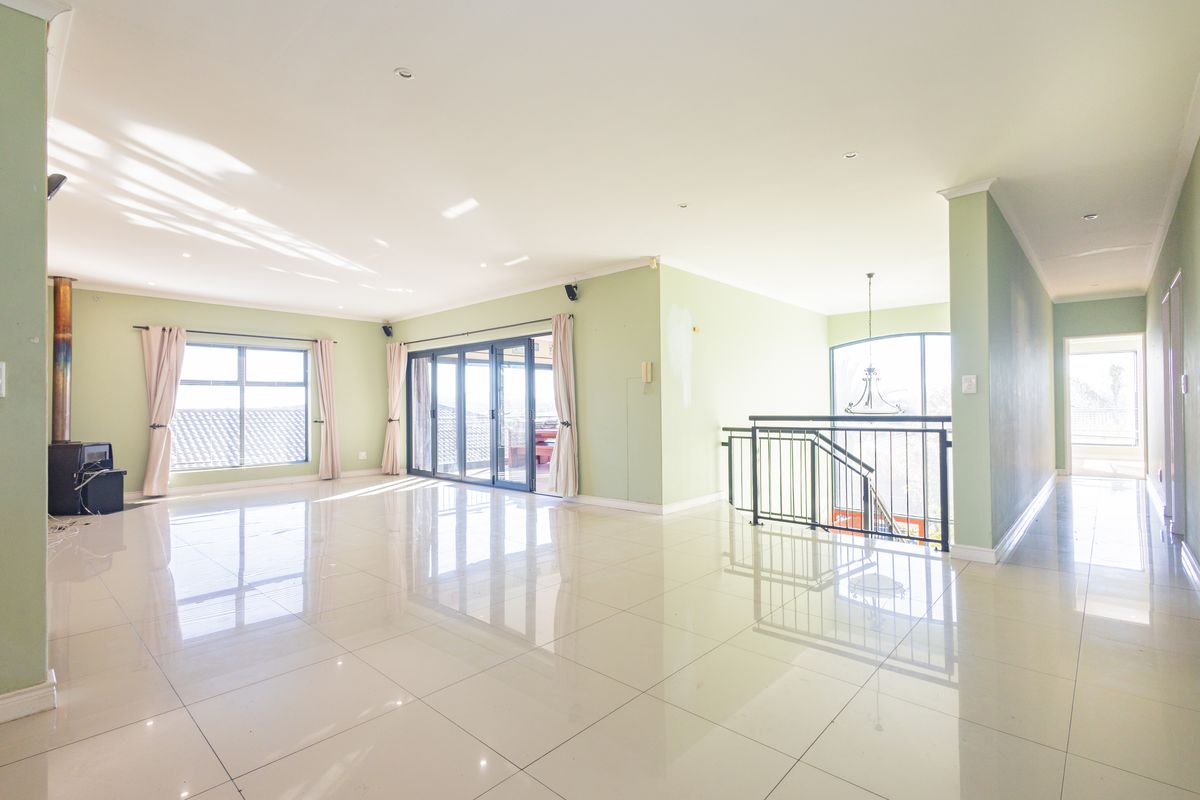 Spacious open-plan living area featuring polished tile flooring, a freestanding fireplace, and large sliding doors leading to an outdoor space.