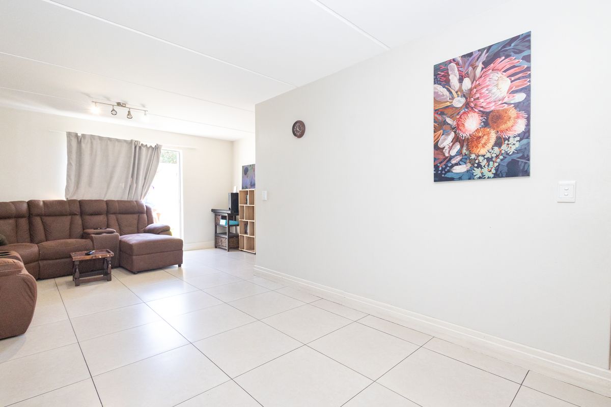 A bright living room featuring neutral tiled flooring and a sliding glass door providing access to the outdoor area.
