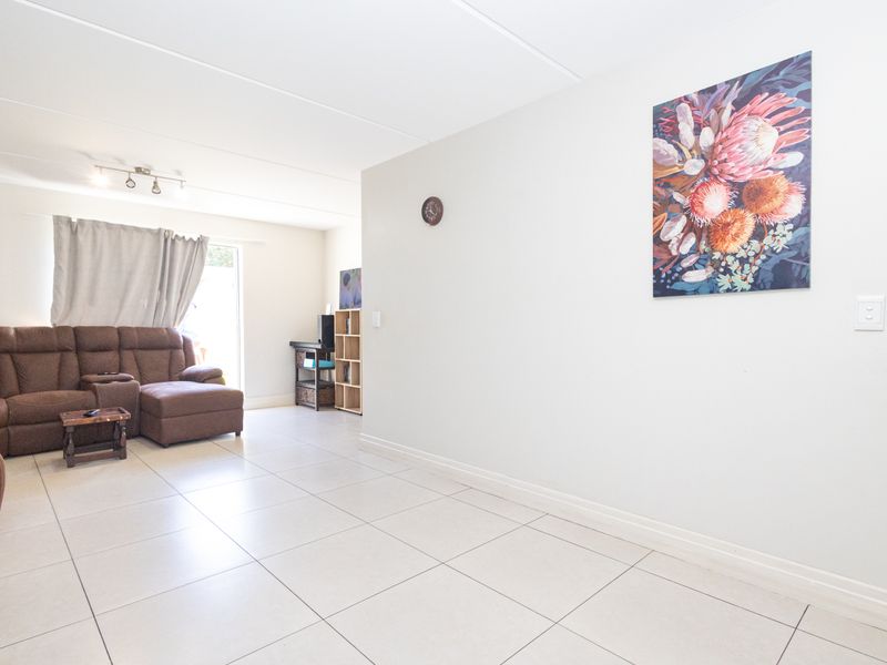 A bright living room featuring neutral tiled flooring and a sliding glass door providing access to the outdoor area.