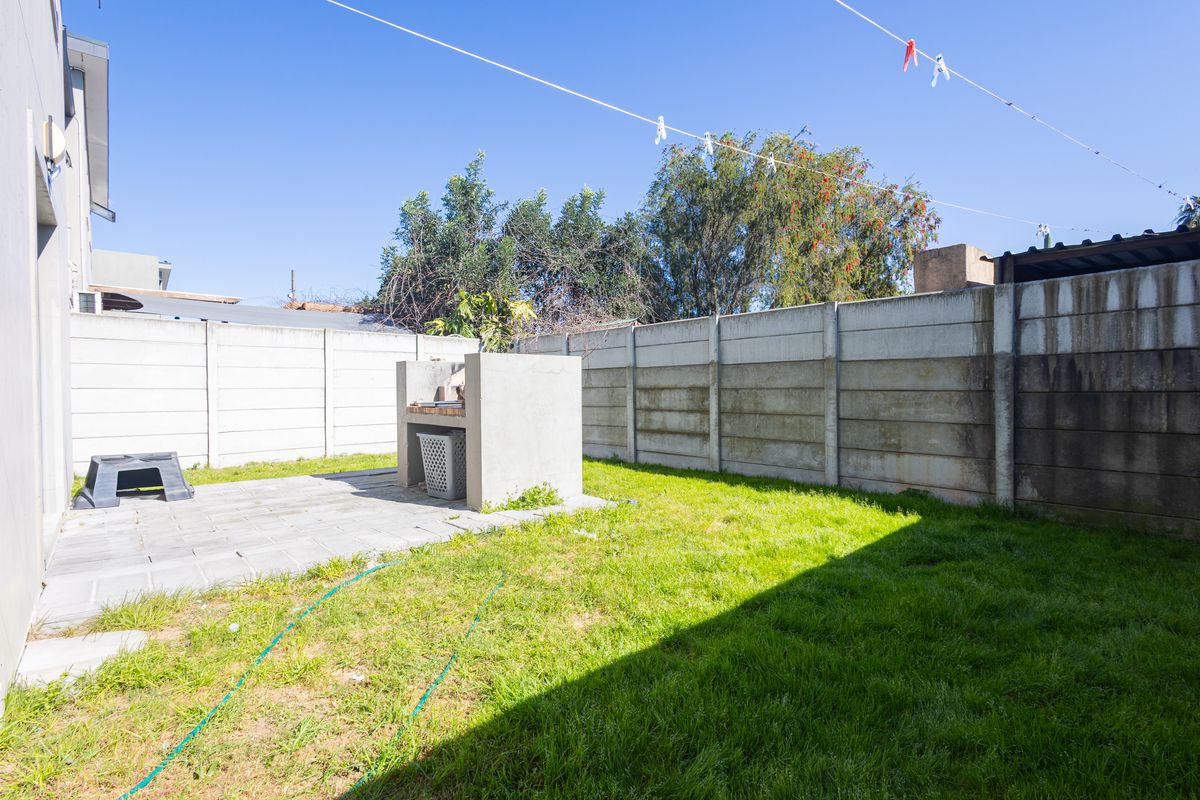 Private rear garden featuring a paved patio area with a built-in braai and enclosed by precast concrete boundary walls.