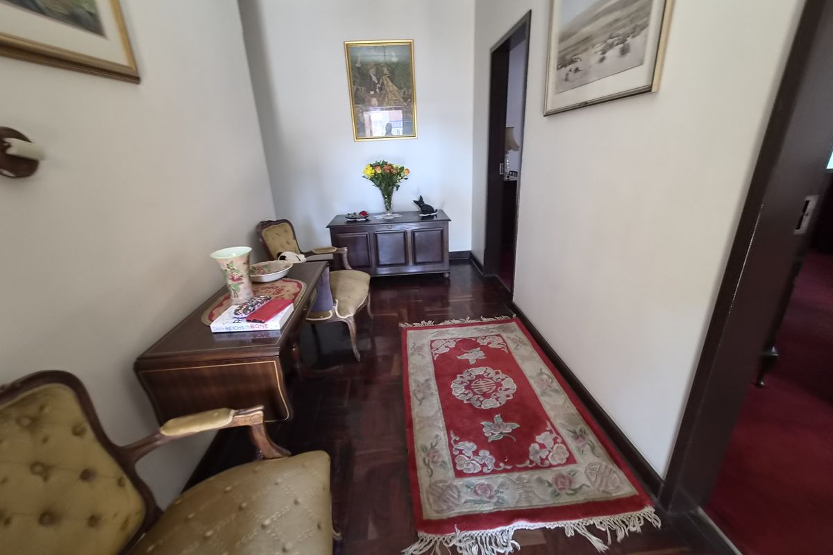 A well-maintained hallway featuring classic parquet flooring and coved ceiling details, providing a warm and traditional transition between living spaces.