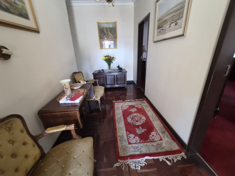 A well-maintained hallway featuring classic parquet flooring and coved ceiling details, providing a warm and traditional transition between living spaces.