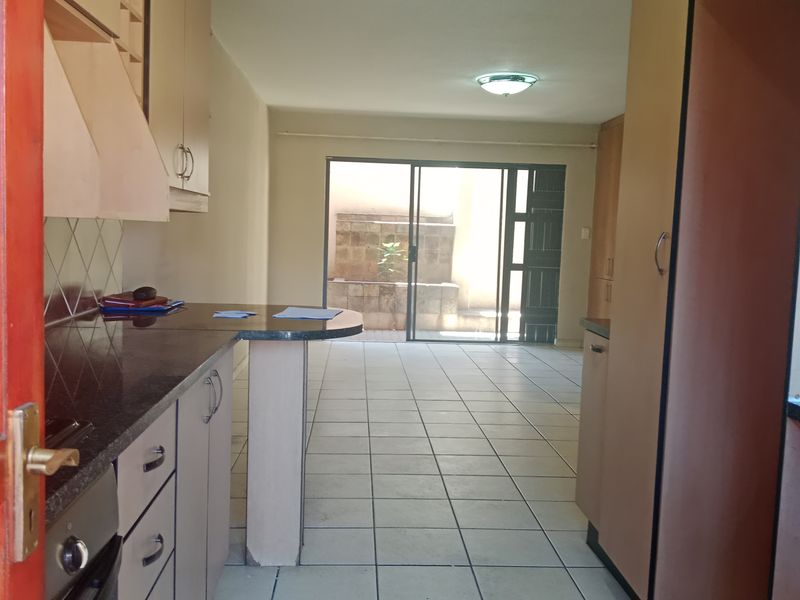 Open plan kitchen and living area featuring tiled floors, granite countertops, and a sliding glass door leading to a private rear patio.