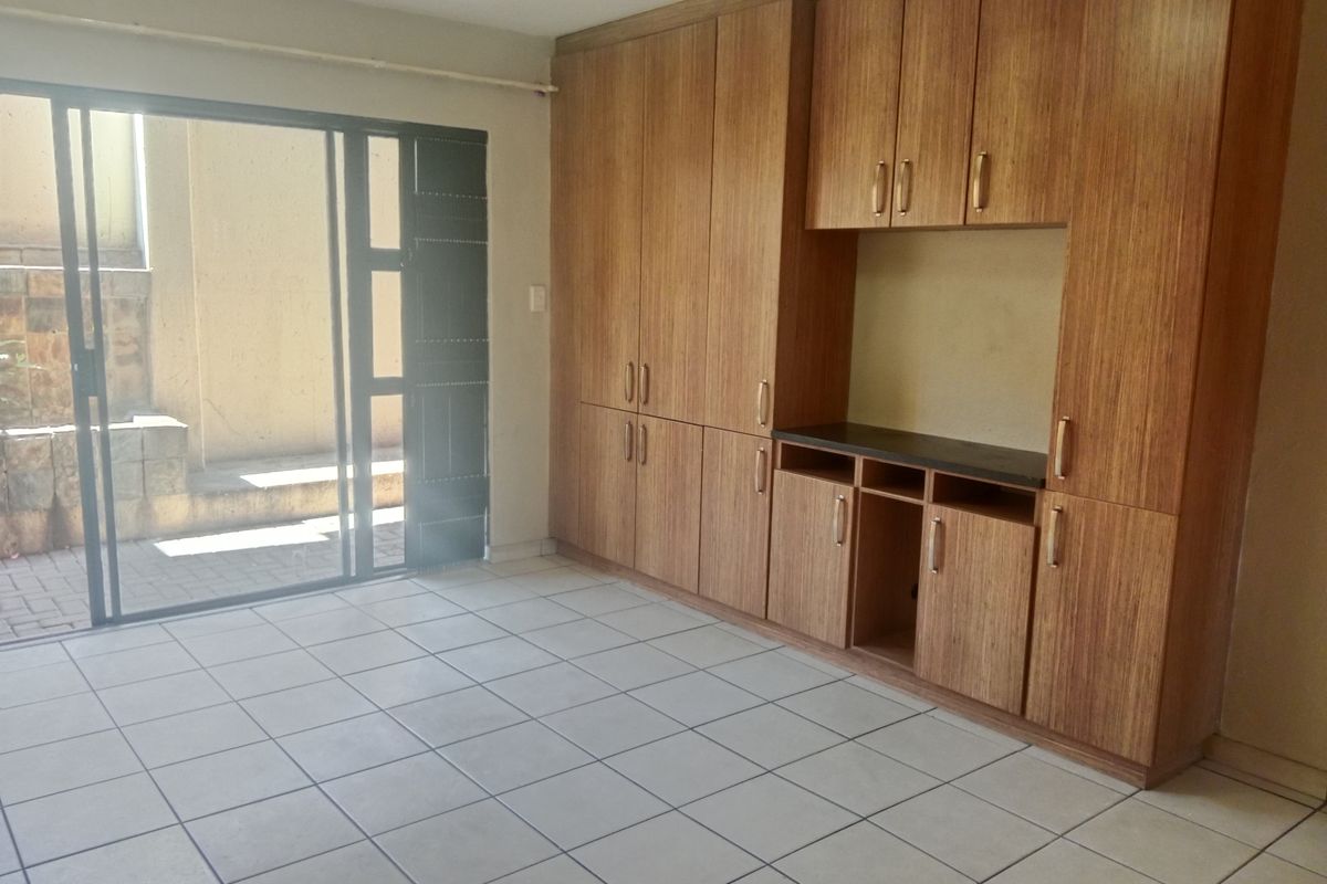 An empty living area featuring light wood-grain built-in cabinetry and a sliding glass door providing access to an outdoor patio space.
