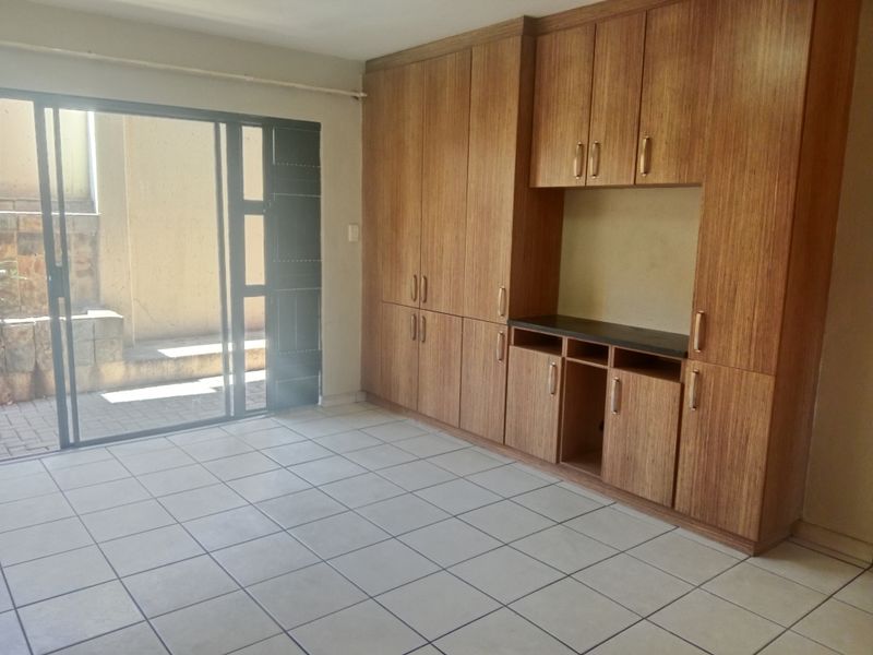 An empty living area featuring light wood-grain built-in cabinetry and a sliding glass door providing access to an outdoor patio space.