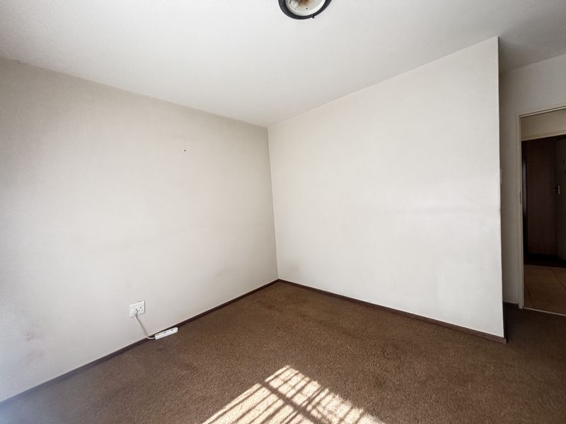 An empty bedroom featuring neutral walls and carpet flooring, providing a blank canvas for personalization.