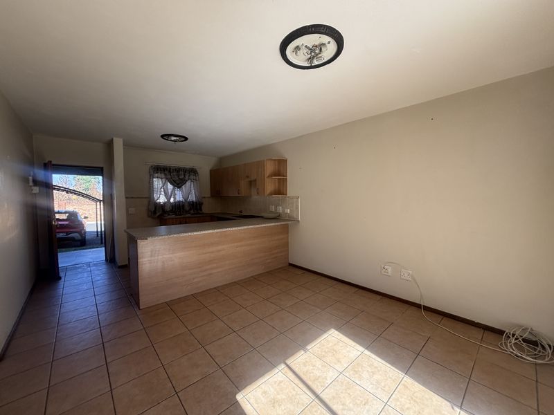 Open-plan living and kitchen area featuring tiled flooring, built-in cabinetry, and a breakfast counter, offering a functional space ready for modernization.