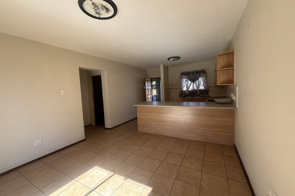 Open plan living and kitchen area featuring tiled flooring and a breakfast bar, offering a functional layout ready for personalization.