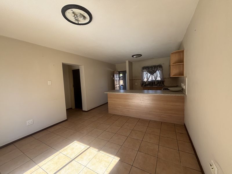 Open plan living and kitchen area featuring tiled flooring and a breakfast bar, offering a functional layout ready for personalization.