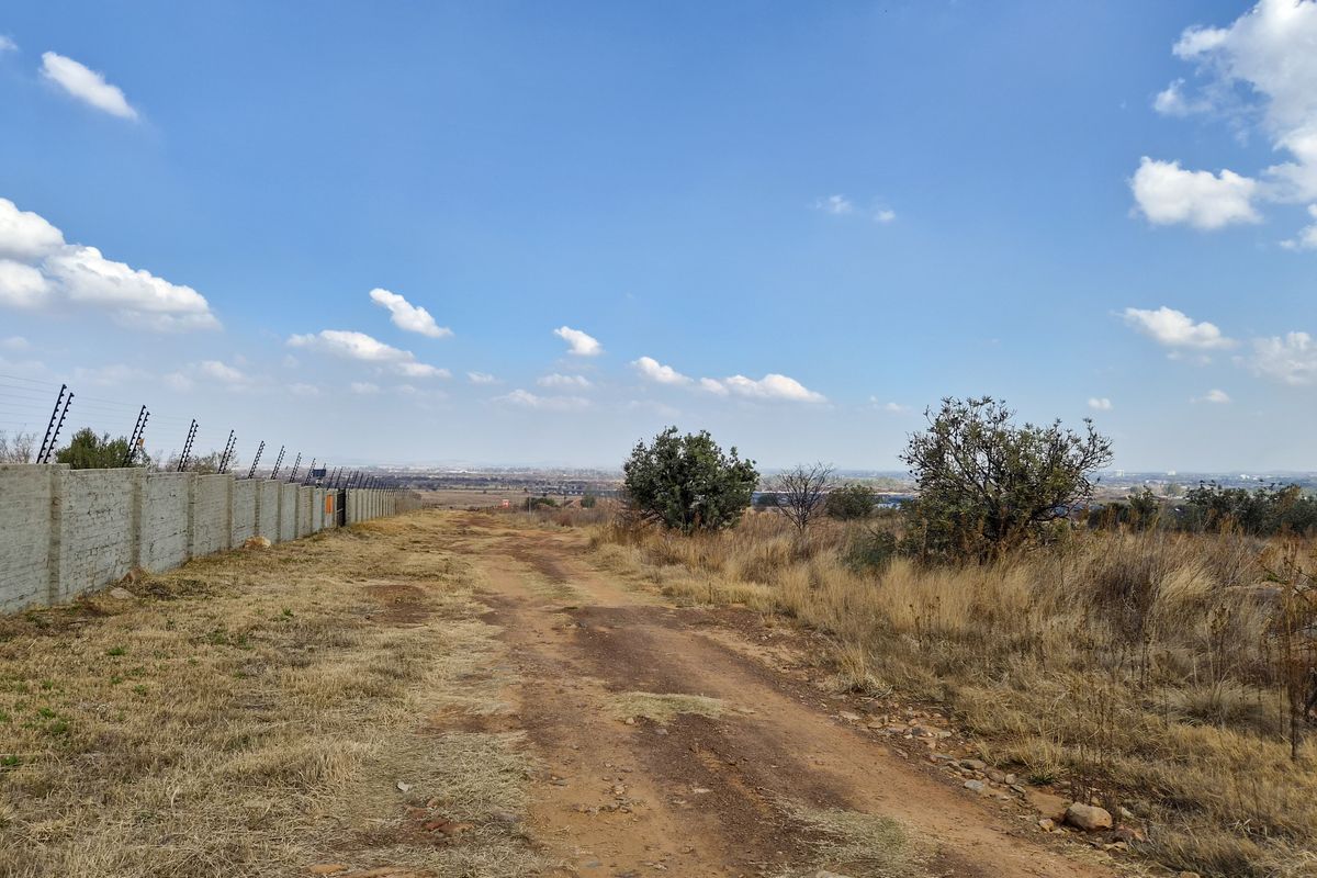 A view across the vacant residential land, featuring a perimeter wall with electric fencing and natural landscape.