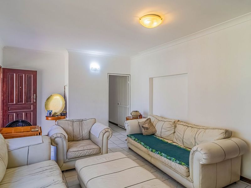 A living room featuring tiled flooring, cove cornicing, and a built-in wall niche, providing a functional and neutral space.