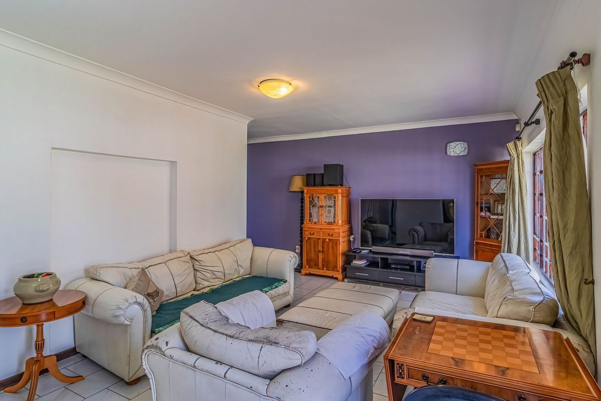A living room featuring tiled flooring, cove cornicing, and a feature wall, offering a functional space ready for modern updates.