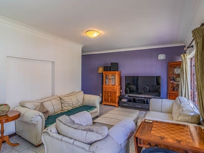 A living room featuring tiled flooring, cove cornicing, and a feature wall, offering a functional space ready for modern updates.