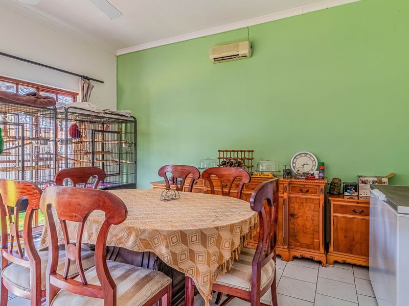 Dining room featuring tiled flooring, a wall-mounted air conditioning unit, and a sliding glass door providing natural light.