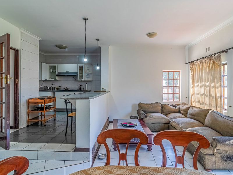 Open-plan living and kitchen area featuring a breakfast bar, tiled flooring, and functional kitchen cabinetry with built-in cooking appliances.
