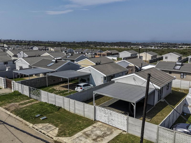 Aerial view of a residential estate featuring detached houses with tiled roofs, metal carports, and enclosed garden areas with boundary walls.