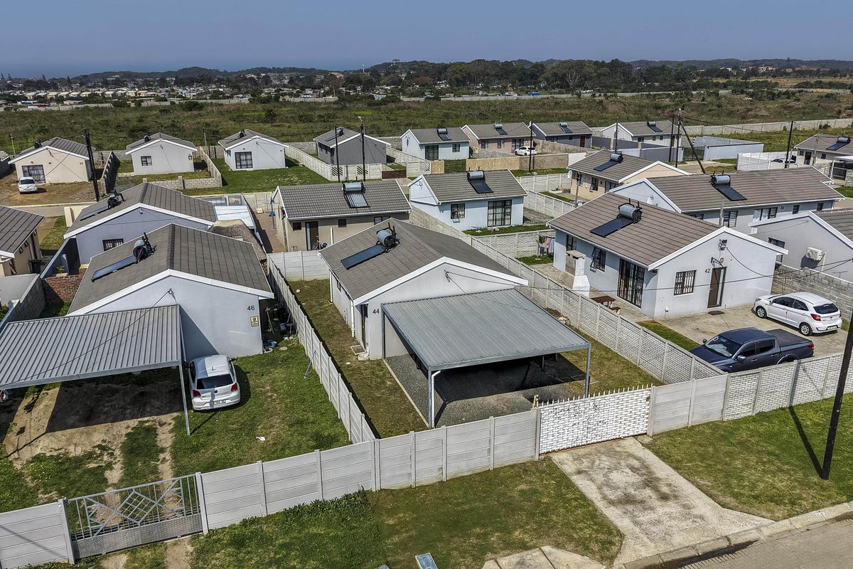 Aerial view of a residential estate featuring detached houses with tiled roofs, solar geysers, private carports, and enclosed garden spaces with boundary walls.