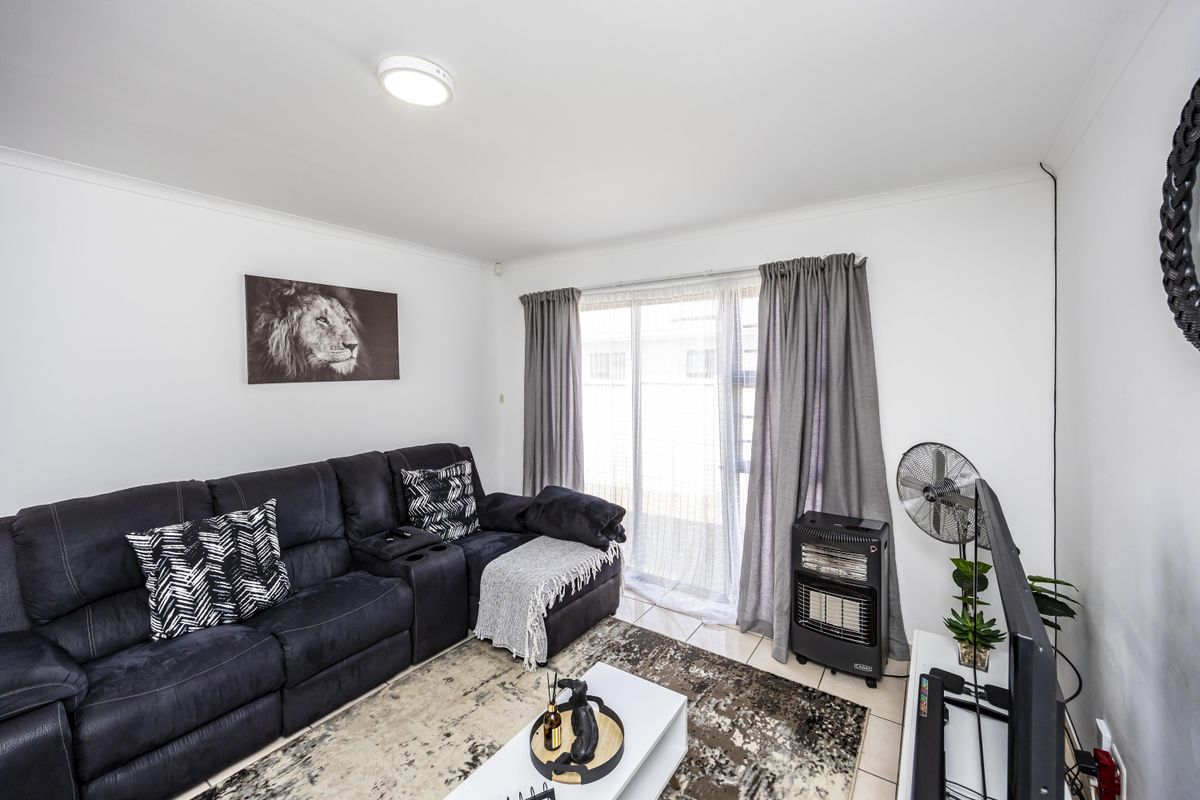 A bright living room featuring tiled flooring and a sliding glass door providing access to the exterior.