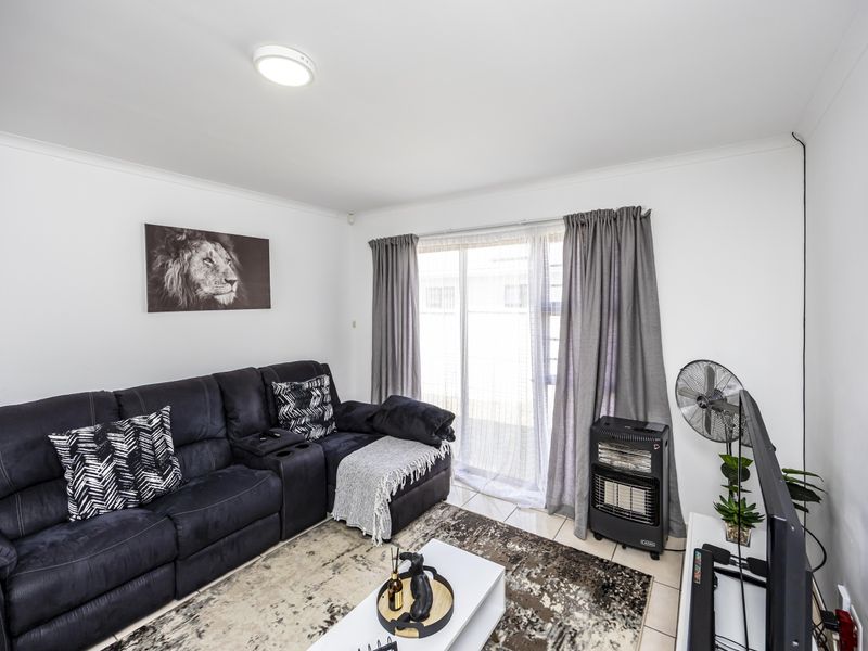 A bright living room featuring tiled flooring and a sliding glass door providing access to the exterior.