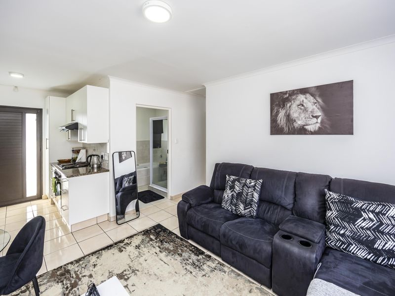 An open-plan living area featuring a compact kitchen with built-in cabinetry and tiled flooring, seamlessly connected to the main living space.