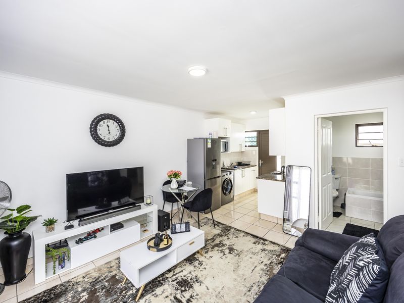 Open-plan living area featuring tiled floors, a modern kitchen with granite countertops, and direct access to an adjacent bathroom.