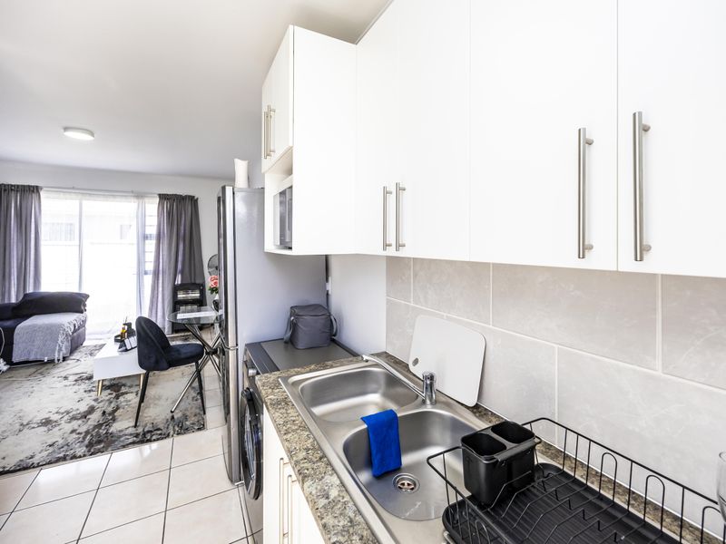 Open plan kitchen and living area featuring modern white cabinetry, tiled splashbacks, and durable tiled flooring throughout the space.