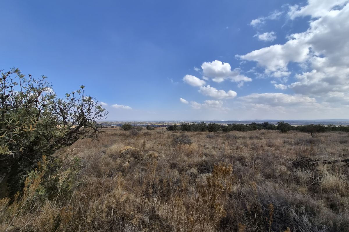 A wide-angle view of the vacant residential land, featuring natural dry grassland and distant horizon views under a clear blue sky.