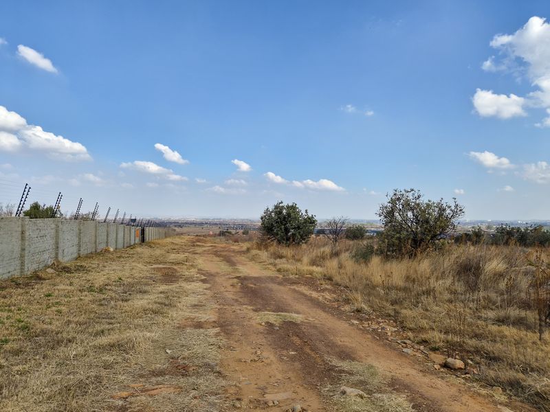 A view across the vacant residential land, featuring a perimeter wall with electric fencing and natural landscape.