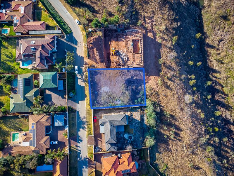 An aerial view of a vacant residential plot situated in a developed neighborhood, highlighting the land boundaries and surrounding residential properties.