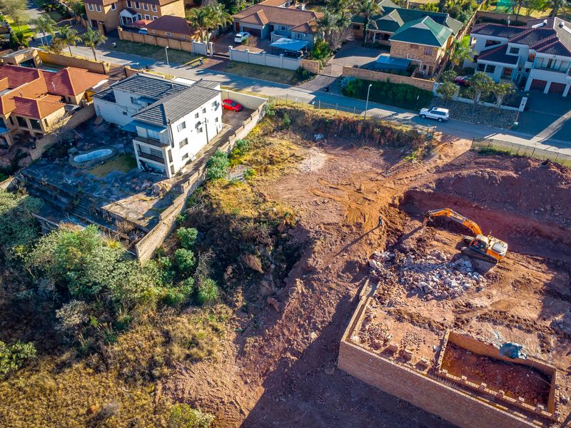 Aerial view of a residential vacant land plot showing active excavation and foundation work in progress.