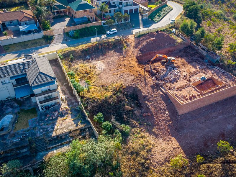 Aerial view of a residential vacant land plot showing active excavation and foundation work in progress.