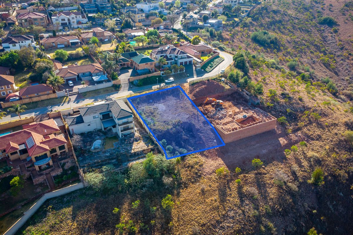 Aerial view of a vacant residential plot situated in a developed suburban hillside neighborhood, ready for new construction.