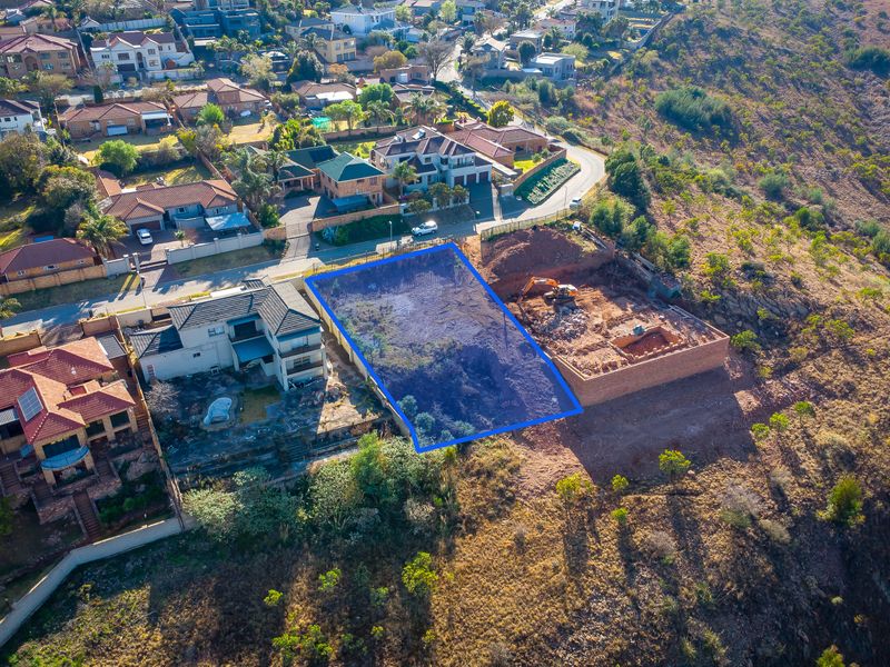 Aerial view of a vacant residential plot situated in a developed suburban hillside neighborhood, ready for new construction.