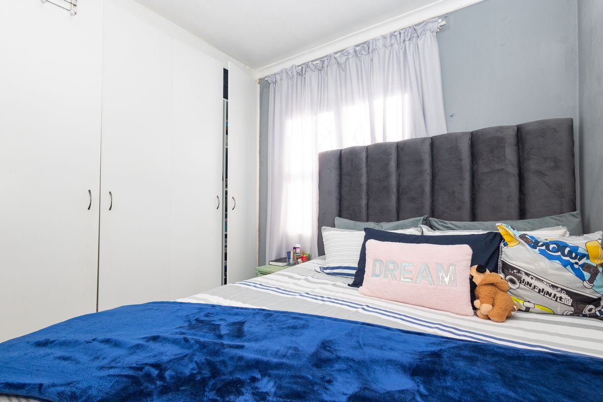 A bedroom featuring built-in cupboards and natural light through a window with curtain rails.