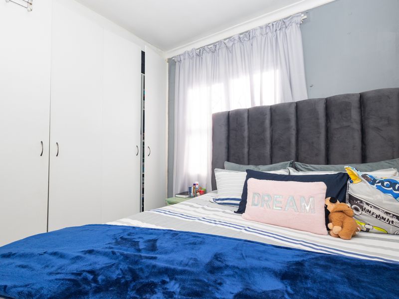 A bedroom featuring built-in cupboards and natural light through a window with curtain rails.