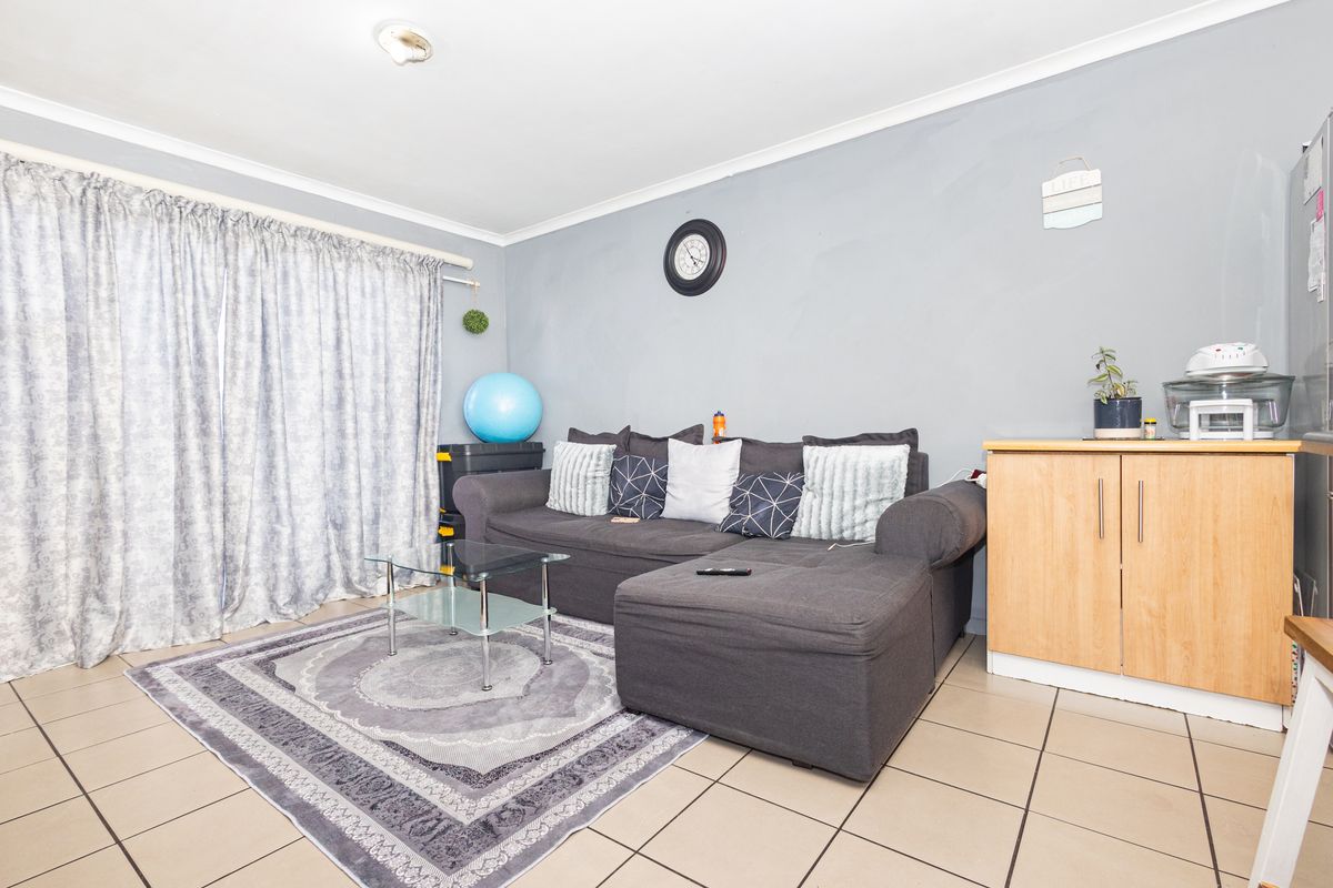 A living room area featuring neutral tiled flooring and grey painted walls, providing a functional space for relaxation.