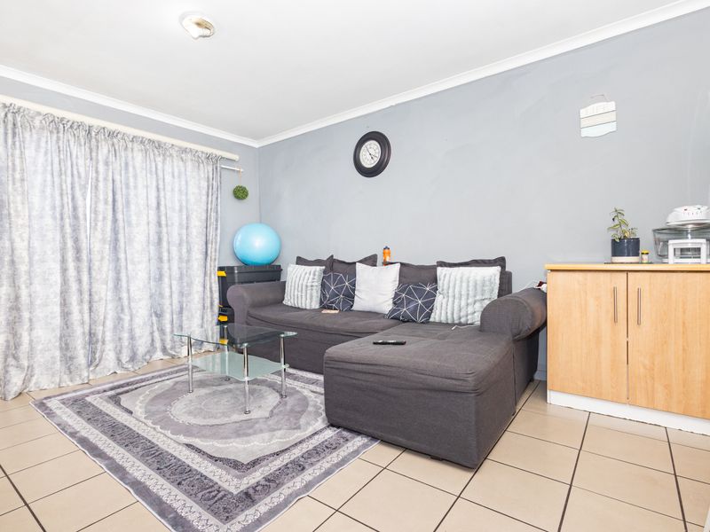 A living room area featuring neutral tiled flooring and grey painted walls, providing a functional space for relaxation.