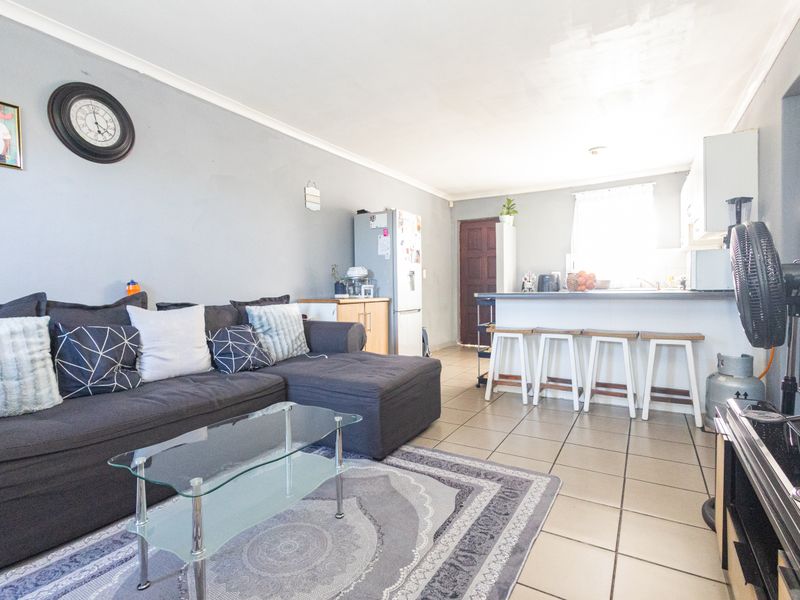 Open-plan living area featuring tiled flooring, a breakfast bar, and integrated kitchen cabinetry, creating a functional and connected space.