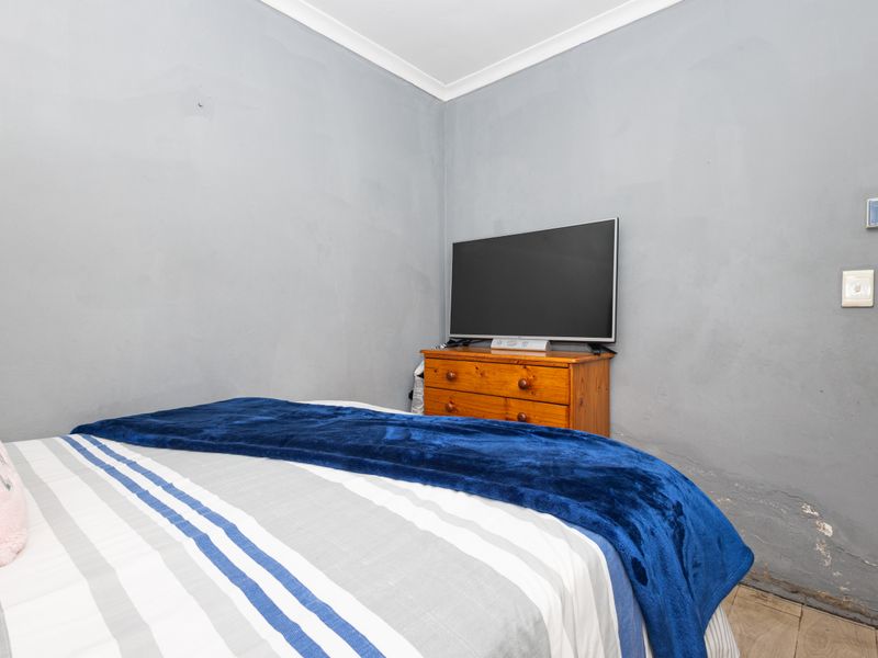 A bedroom featuring grey walls with visible surface wear and damage near the base, requiring cosmetic attention and repair.