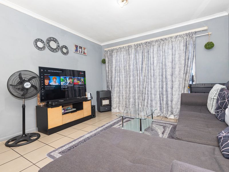 A functional living room featuring tiled flooring and neutral wall finishes, providing a comfortable space for relaxation and entertainment.