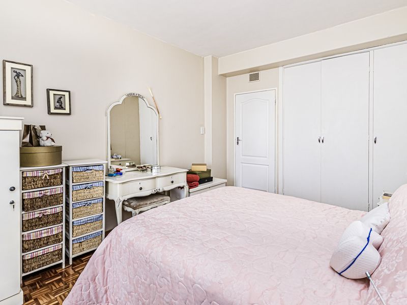 A bedroom featuring classic parquet flooring and ample built-in cupboard storage space.