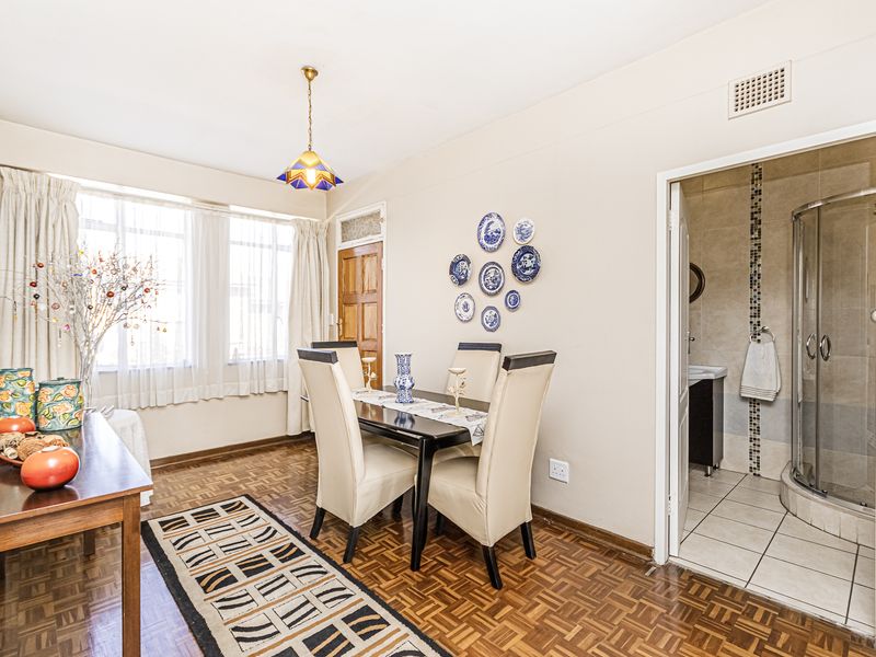 Dining area featuring classic parquet flooring and direct access to an adjacent bathroom with a glass shower enclosure.