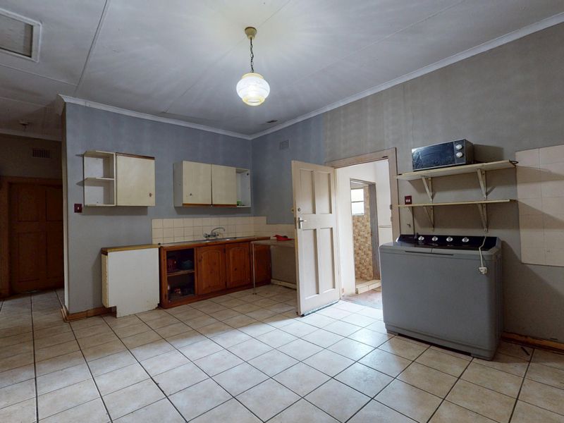 A functional kitchen area featuring tiled flooring, built-in cabinetry, and a sink, offering a blank canvas for potential renovation and modernization.