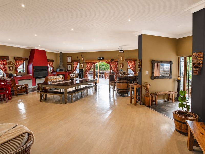 Spacious open-plan living area featuring timber flooring, a prominent built-in fireplace, and direct access to an outdoor patio through sliding glass doors.