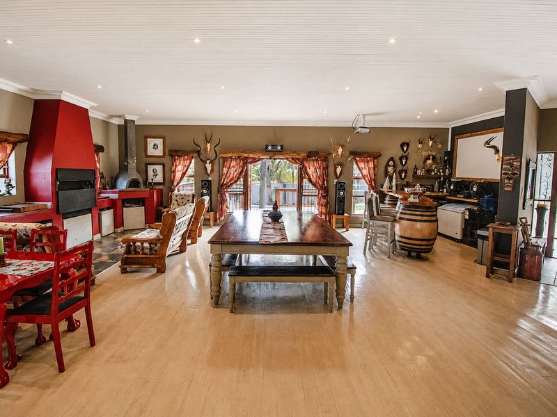 Spacious open-plan living and entertainment area featuring a built-in fireplace, pizza oven, and a dedicated bar section with timber flooring throughout.