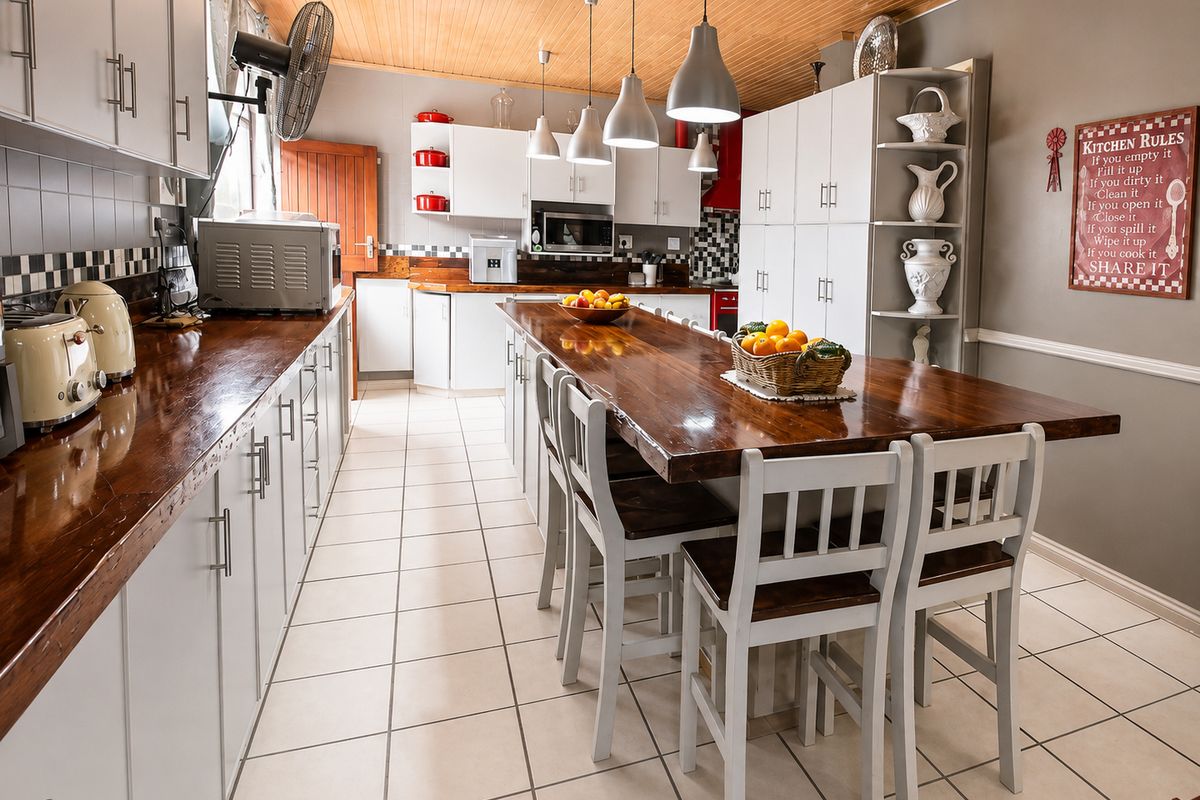 Spacious kitchen featuring timber ceilings, tiled flooring, extensive built-in cabinetry, wooden countertops, and a large central island with integrated seating.
