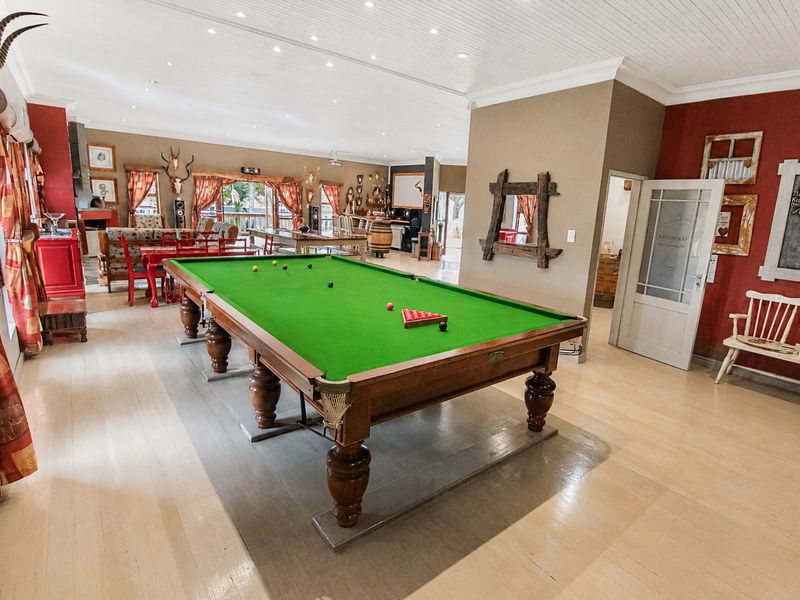 Spacious open-plan living area featuring timber flooring, recessed downlighting, and a beadboard ceiling, currently configured as a recreational space.