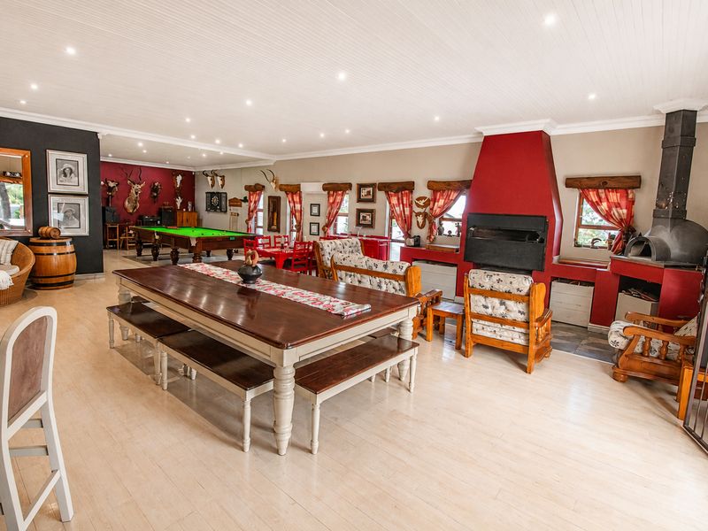 Spacious open-plan living and entertainment area featuring a built-in fireplace, pizza oven, and light timber-look flooring throughout.