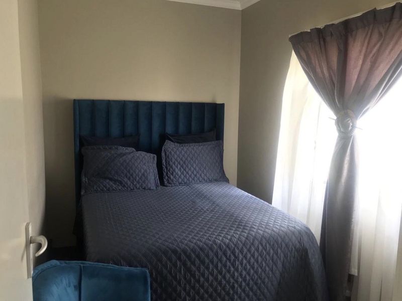 A compact bedroom featuring neutral wall tones and natural light from a side window.