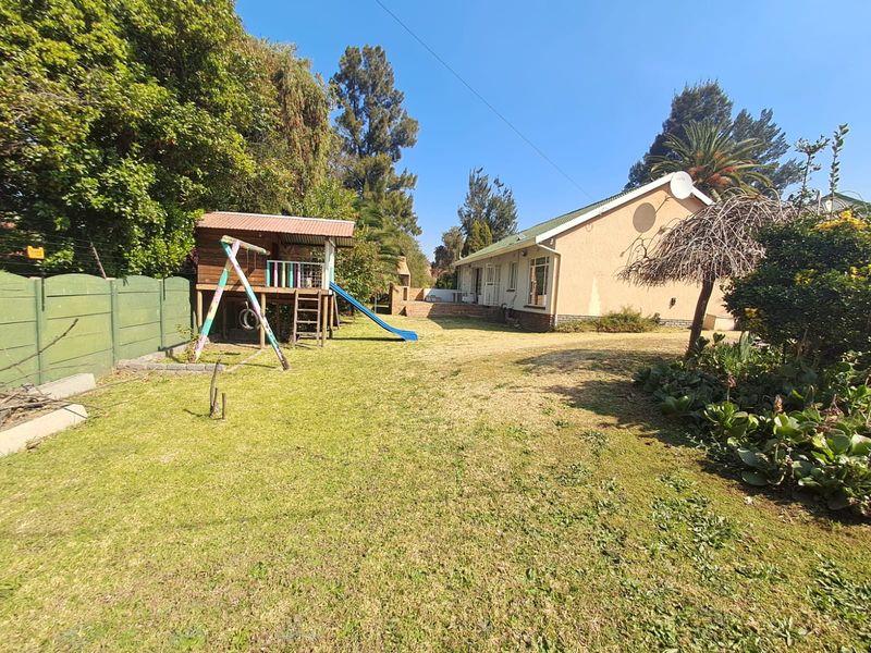 Spacious rear garden featuring a lawn, perimeter wall, and a built-in outdoor braai area, providing a functional space for outdoor activities.